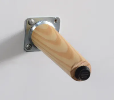 A close-up of a wooden furniture leg attached to a metal plate, mounted on a white surface.