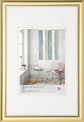 A framed picture of a room interior with a chair and a small table.