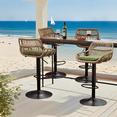 Bar stools and a table set up on a deck overlooking a beach and the ocean.