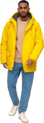 A man wearing a yellow jacket and blue jeans.