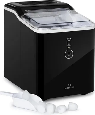 A black ice maker with a transparent lid and a white ice scoop with ice cubes in front of it, set against a white background.
