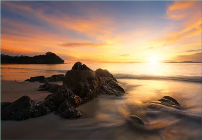 Produktbild von Wallario Fototapete Vliestapete, seidenmatte Oberfläche, einfache Verarbeitung, Größe 200 x 140 cm, Motiv Sonne über dem Meer mit Felsenlandschaft