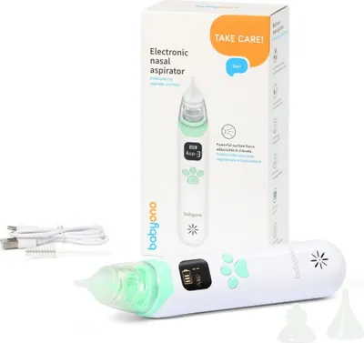 A white electronic nasal aspirator with green accents and its packaging are displayed against a white background. A USB charging cable and cleaning brush are also visible.