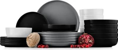A collection of dinnerware in various colors and sizes, along with some decorative elements like a nut and cranberries.