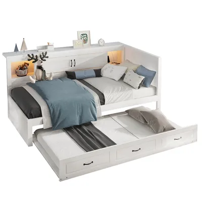 A white daybed with a pull-out trundle bed, decorated with pillows and a stuffed reindeer.