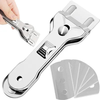 A close-up shot of a glass scraper and spare blades against a white background. A hand is shown holding a smaller part of the scraper.