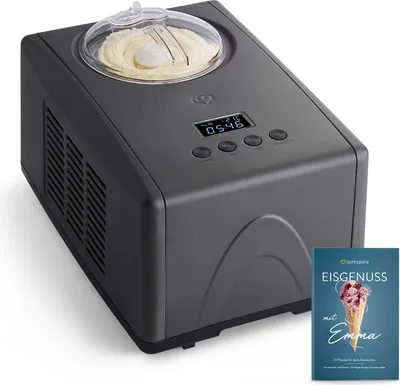 A dark gray ice cream maker with a clear lid and ice cream inside, placed on a white background. A book with an ice cream cone on the cover is placed to the right of the ice cream maker.