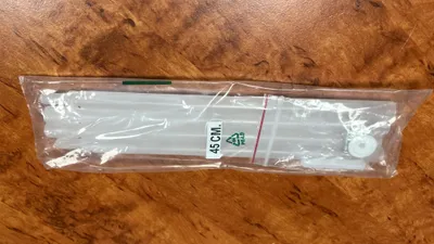 A clear plastic package containing several white rods, lying on a wooden surface.
