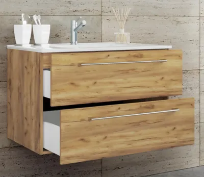 A wall-mounted bathroom vanity with two drawers, one of which is partially open, showing the white interior. The vanity has a wood-grain finish and silver handles. A white countertop with a sink and faucet is visible at the top. Two white toothbrush holder