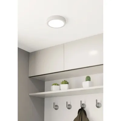 A ceiling light fixture in a modern room with cabinets and shelves.