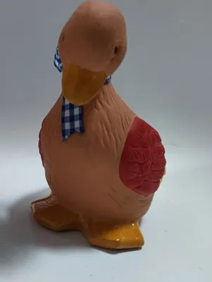 Niedliche Ente aus Terrakotta. Sie ist in sanften Erdtönen gehalten und hat blaue und rote Akzente.