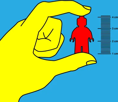 A hand holding a small red LEGO figure next to a ruler.