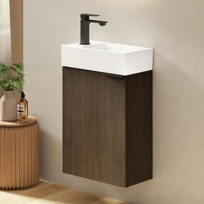 A wall-mounted bathroom vanity with a white ceramic sink and a dark wood cabinet.