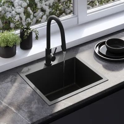 A modern kitchen sink with a black faucet, set against a window with white flowers.