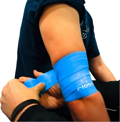 A person's arm is shown with a blue flossband being wrapped around it.