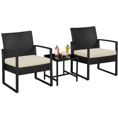 Two black rattan chairs with beige cushions and a small black side table with drinks and snacks, set against a white background.
