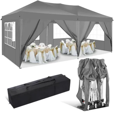 A grey pop-up gazebo set up with tables and chairs inside, along with a folded gazebo and a carrying bag.
