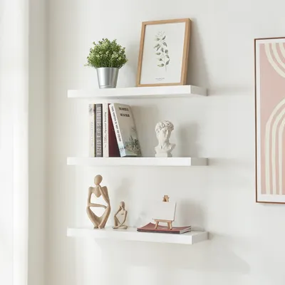 Three white floating shelves mounted on a white wall, decorated with various items.