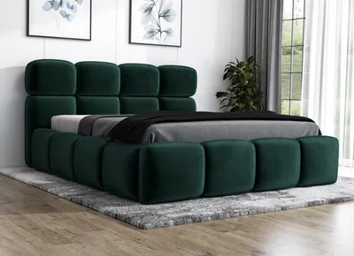 A green upholstered bed with a tufted headboard and frame, placed on a gray rug in a room with artwork on the wall and curtains in the background.
