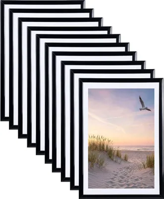 A stack of black picture frames, with one frame displaying a beach scene with a bird flying.
