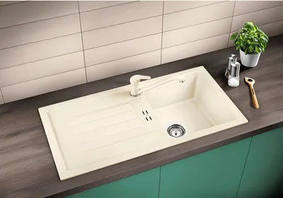 A kitchen sink with a faucet, drain, and a drying rack area, set against a tiled backsplash.