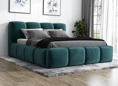 A green upholstered bed with a headboard and frame, set up in a bedroom with a rug and artwork on the wall.
