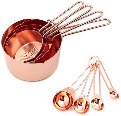 A set of copper-colored measuring cups and spoons arranged on a white background.