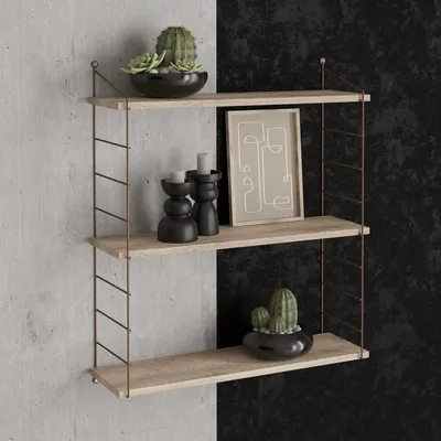 A three-tiered wall shelf with decorative items on a split concrete and black textured wall.