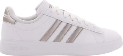 A side view of a white Adidas sneaker with silver stripes.