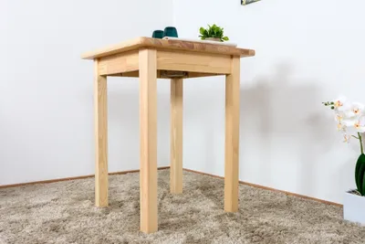 A small wooden table is shown in a room with a light-colored carpet and white walls. There are two green cups and a small plant on the table. A white pot with a white orchid is visible on the right side of the image.
