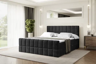 A bedroom scene featuring a large black upholstered bed.