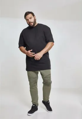 A man wearing a black t-shirt and green pants.