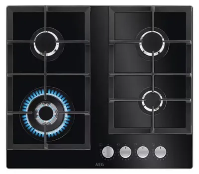 A top-down view of a black gas hob with four burners, one of which is lit with a blue flame. The hob has a black glass surface and silver control knobs at the bottom.