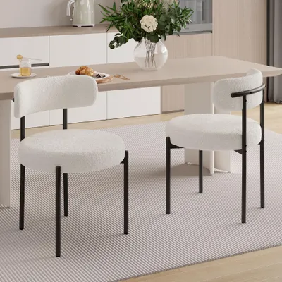 Two white boucle chairs are placed around a dining table in a modern kitchen setting.