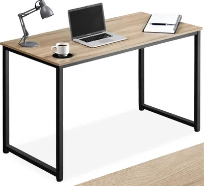 A wooden desk with black metal legs, a laptop, a cup of coffee, and a desk lamp.