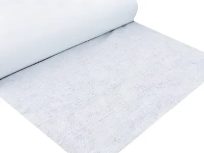 A roll of white drainage fleece is partially unrolled on a white surface.