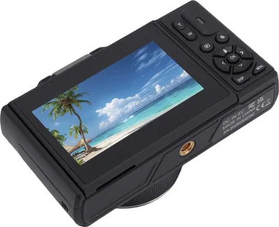 The back of a black digital camera displaying a tropical beach scene on its screen.