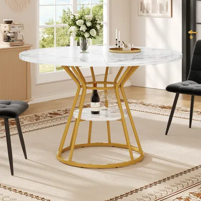 A round dining table with a marble-look top and gold metal legs, set in a dining room with chairs and a rug.