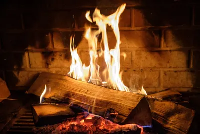 A close-up shot of a fire burning in a fireplace with logs and bricks visible.