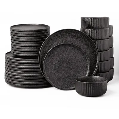 A set of black ceramic plates and bowls are neatly stacked against a white background.