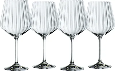 Four clear wine glasses with vertical ribbed texture are arranged in a row against a white background.