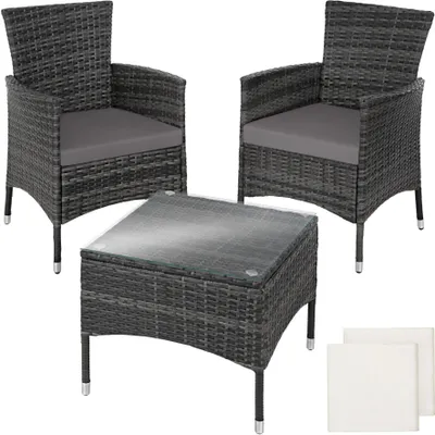 A set of two rattan chairs and a coffee table with a glass top, presented on a white background.