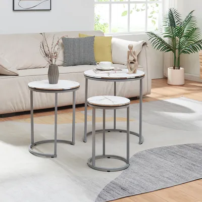 A living room scene with a sofa, a plant, and a set of nesting tables.