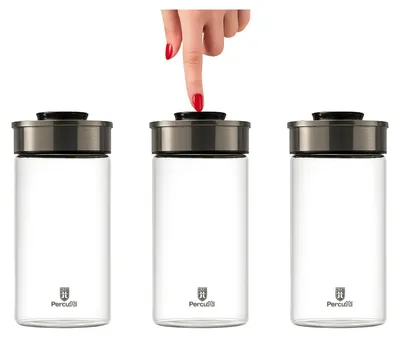 Three glass storage jars with metal lids are shown against a white background. A hand is pressing the lid of the middle jar.