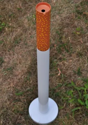 A cigarette-shaped ashtray standing on a grassy area.