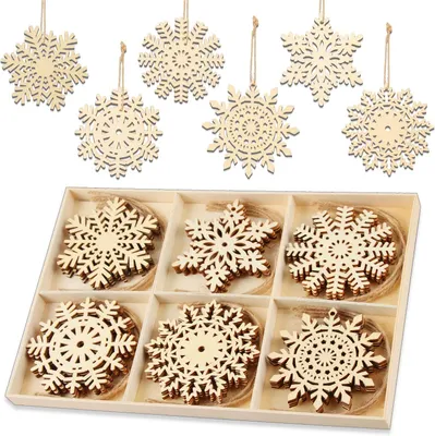 A set of wooden snowflake ornaments in a divided box, with some ornaments hanging above.