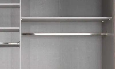 Close-up view of empty shelves and a clothes rack in a closet.