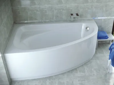 A white corner bathtub with a curved front panel, set against a tiled wall and floor.