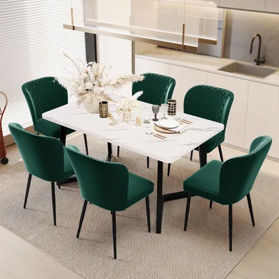 A dining set with a marble-top table and six green velvet chairs in a modern kitchen setting.