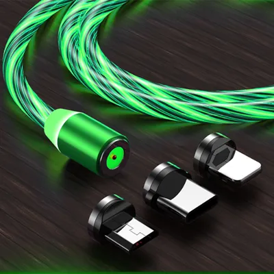 A glowing green charging cable with three magnetic adapters on a dark wooden surface.